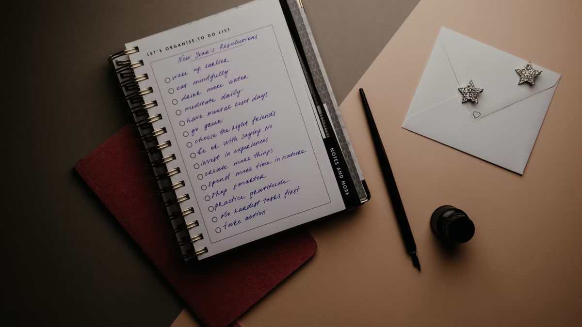 A notebook with new year resolutions and a pen on the desk for organized planning.